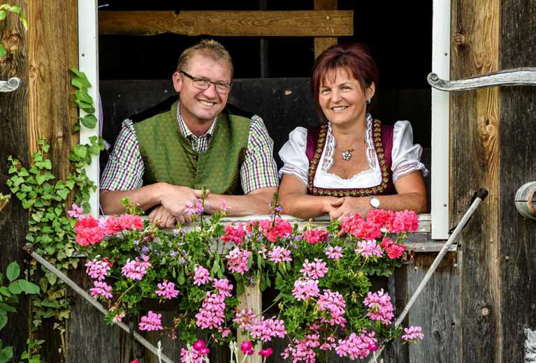 Betreiberehepaar Walter und Monika Müller schaut aus dem mit Geranien behängtem Fenster